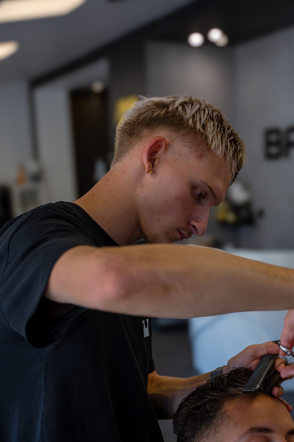 Alex, barbier au salon BarberClub de Meylan, en train de couper aux ciseaux